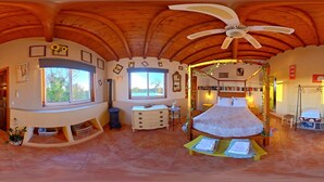 Una habitación con techo abovedado, una cama, un escritorio y un ventanal.