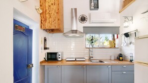Una cocina pequeña con microondas, tostadora y lavamanos.