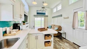 A spacious kitchen with white cabinetry, a central island, and a dining area with a sofa. - Vacation Cottage North Myrtle Beach #65 (North Myrtle Beach)