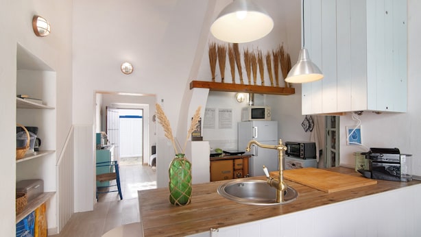 Een keuken met een houten aanrecht, een roestvrijstalen spoelbak en hangende lampen.