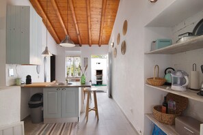 Una cocina con vigas de madera, un fregadero, taburetes y estantes con electrodomésticos.