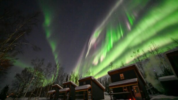 Une rangée de cabanes offrant une vue sur les aurores boréales.