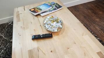 A wooden coffee table with a remote control and a bowl of candies.