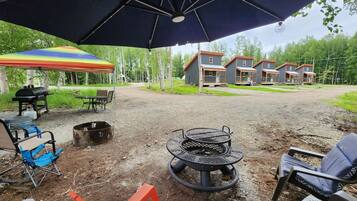 An outdoor patio area with a fire pit, outdoor furniture, and a covered seating area.