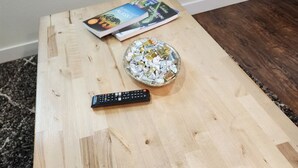 A wooden coffee table with a remote control and a bowl of candies. - The Wandering Wolf - Frontier Village (North Pole)