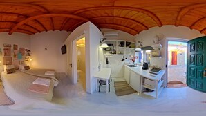 Ein Zimmer mit einem Bett, einem Schreibtisch, einem Stuhl, einem Waschbecken und einer grünen Tür.