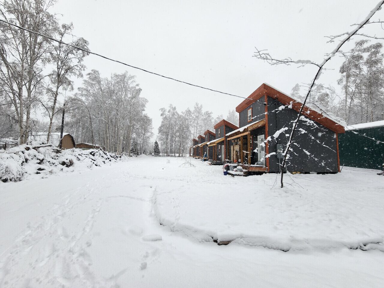A snow-covered outdoor area with a building featuring multiple windows and a porch.