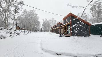 A snow-covered outdoor area with a building featuring multiple windows and a porch.