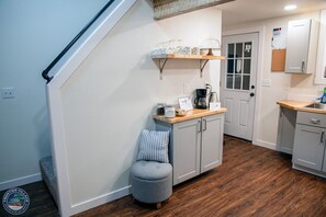 A kitchen with a wooden countertop, a coffee maker, and a small stool.