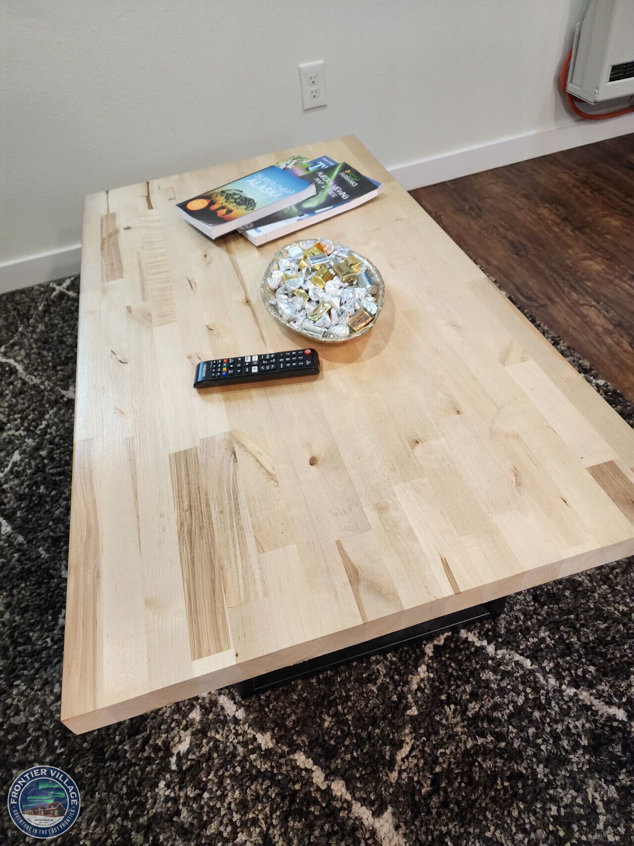 Una mesa de centro de madera con un control remoto y un tazón de caramelos.