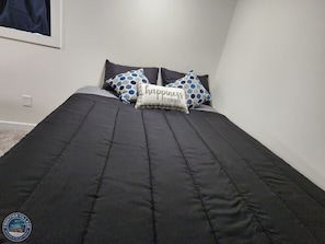 A neatly made bed with a black quilt and two decorative pillows.