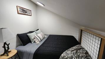 Una camera da letto piccola e curata, con un letto, un comodino con una lampada e un quadro appeso alla parete.
