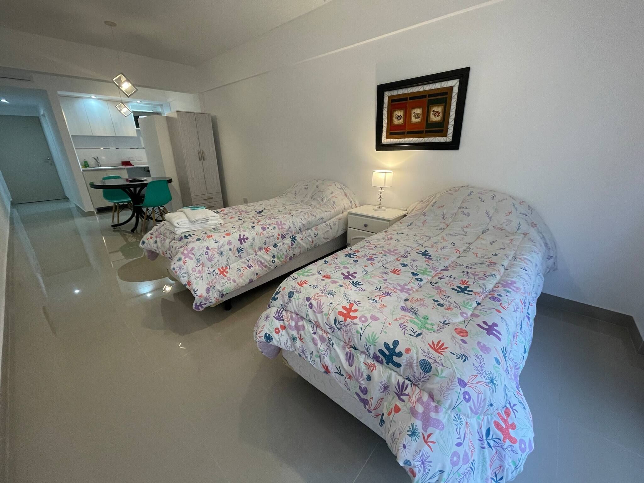 A hotel room with two beds, a dining area, and a kitchenette.