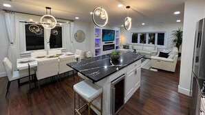 Une cuisine moderne dotée d’un îlot central, de meubles blancs et d’un coin repas avec une table et des chaises blanches.