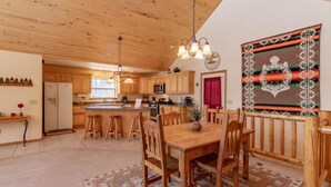 A wooden interior with a dining table, chairs, a kitchen area, and a decorative wall piece. - Pet Friendly TreeHaven Retreat (Pagosa Springs)