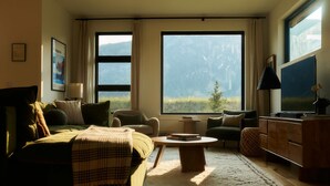 A cozy living room with a large window, a sofa, a coffee table, and a TV.