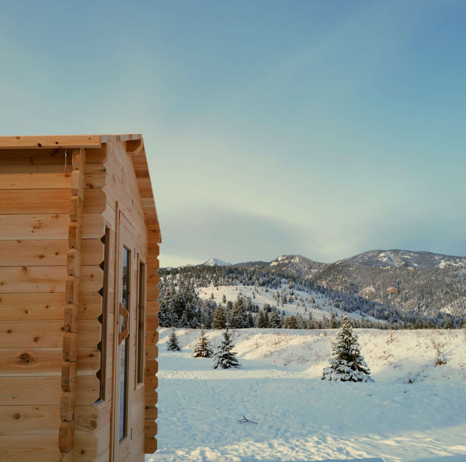 A wooden cabin with a view of a snowy mountain landscape.