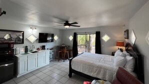 A hotel room with a bed, a desk with a chair, a small kitchen area, and a TV mounted on the wall. - Easy Rider Cabin -Boat/Trailer prkg, Pet ok w/fee (Medicine Park)