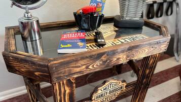 A wooden table with a glass top, a book titled 'The Book of Useless Information', a remote control, and a card holder with cards.