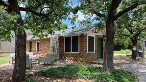 Una cabaña de piedra con un patio, muebles de exterior y un jardín.