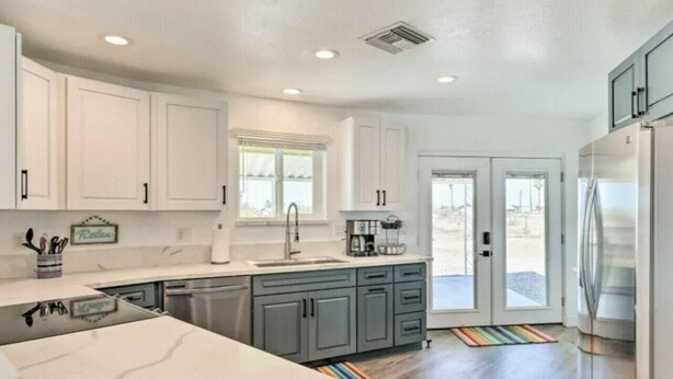 Una cucina moderna con mobili bianchi, un frigorifero in acciaio inossidabile e un'ampia finestra che offre luce naturale.