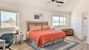 Una camera da letto con un letto, una scrivania, una sedia, una ventola a soffitto e una finestra.