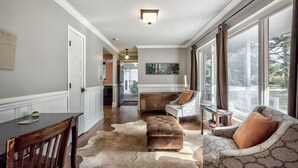 A spacious living area with a large window, a dining table, a sofa, and a rug. - Caught in the City-Walk to BoPlex Coliseum and Ovens Auditorium (Charlotte)