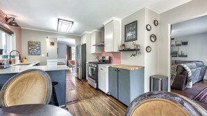 A modern kitchen with a central island, stainless steel appliances, and a dining area with a wooden table and chairs. - Caught in the City-Walk to BoPlex Coliseum and Ovens Auditorium (Charlotte)