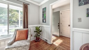 A room with a patterned sofa, a potted plant, and artwork on the walls. - Caught in the City-Walk to BoPlex Coliseum and Ovens Auditorium (Charlotte)