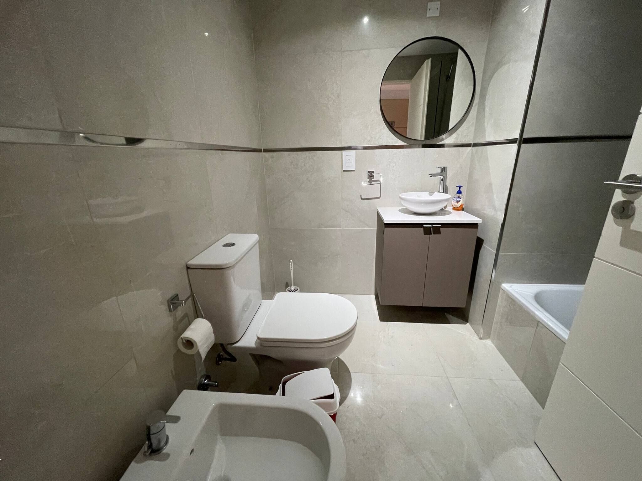 Ein modernes Badezimmer mit Toilette, Bidet, Waschbecken und Badewanne.