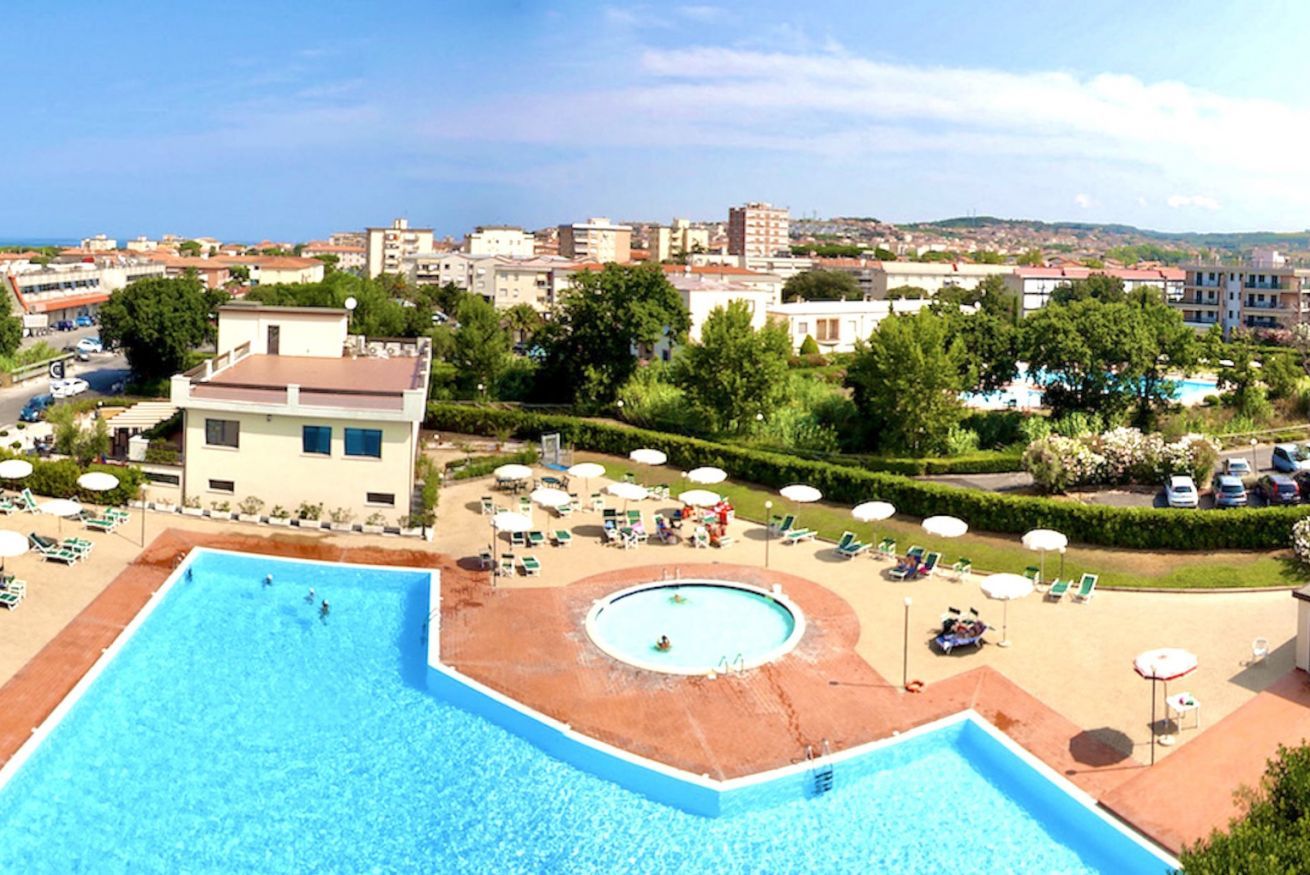 Ein Resort mit einem großen rechteckigen Pool, einem kleineren runden Pool und einem angelegten Bereich mit Liegestühlen und Sonnenschirmen.
