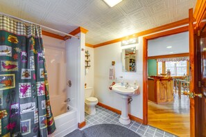 Une salle de bain avec une baignoire, des toilettes, un lavabo et un meuble-lavabo en bois.