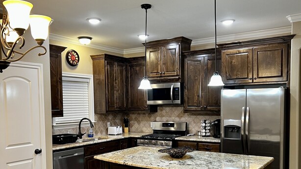 Una cocina moderna con armarios de madera oscura, electrodomésticos de acero inoxidable y una isla grande con taburetes de bar.