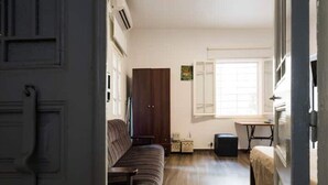 Quarto com sofá, mesa pequena, armário e janela.