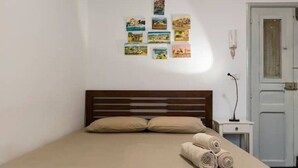 Quarto com cama de madeira, roupa de cama bege e uma colagem de fotos na parede.