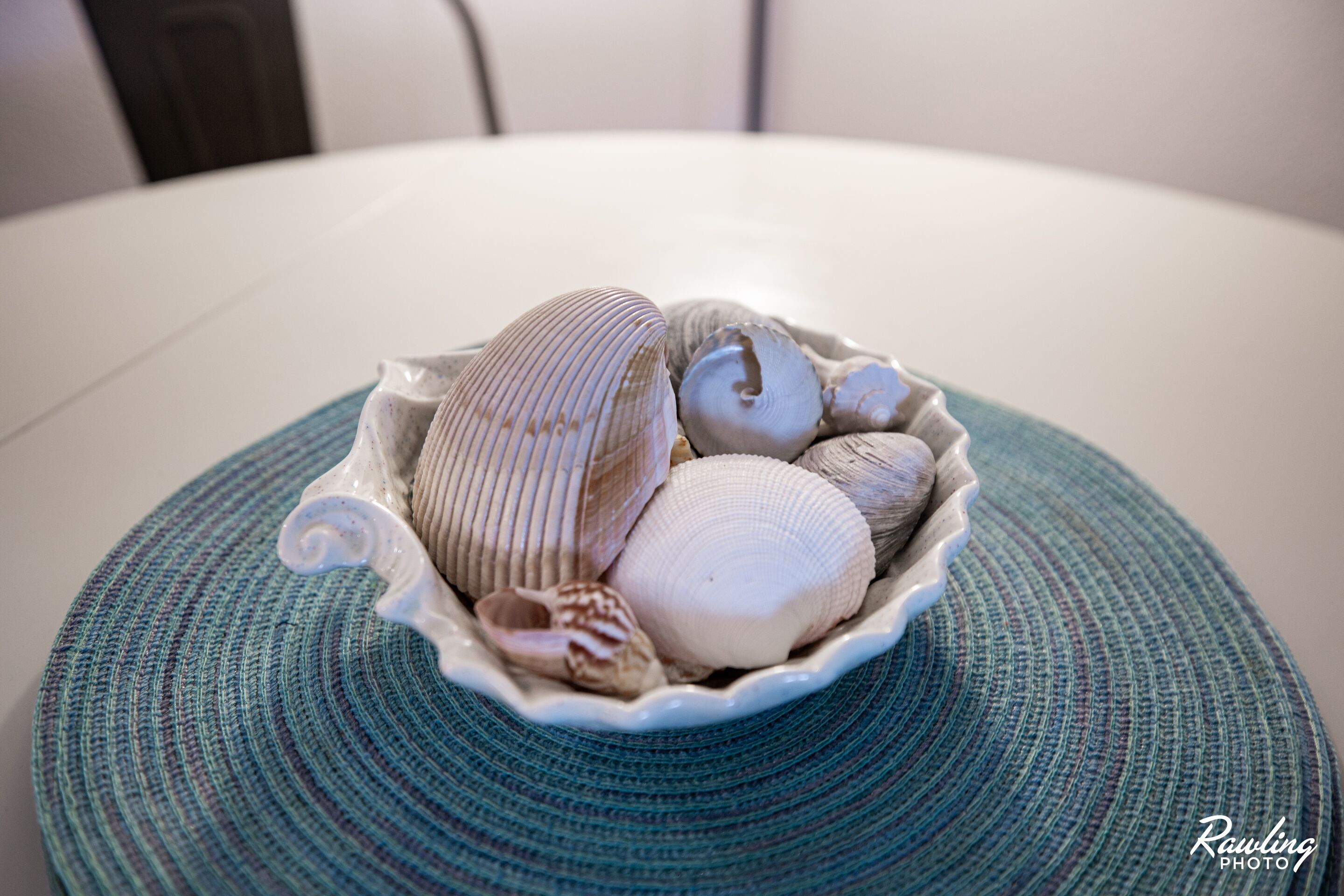 A bowl of seashells on a textured mat.