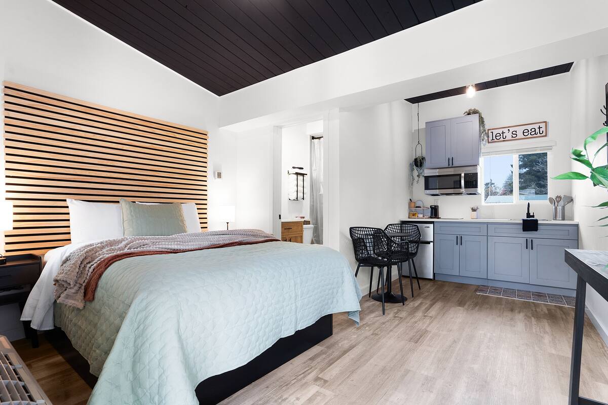 A modern bedroom with a bed, bedside table, and a small desk area.