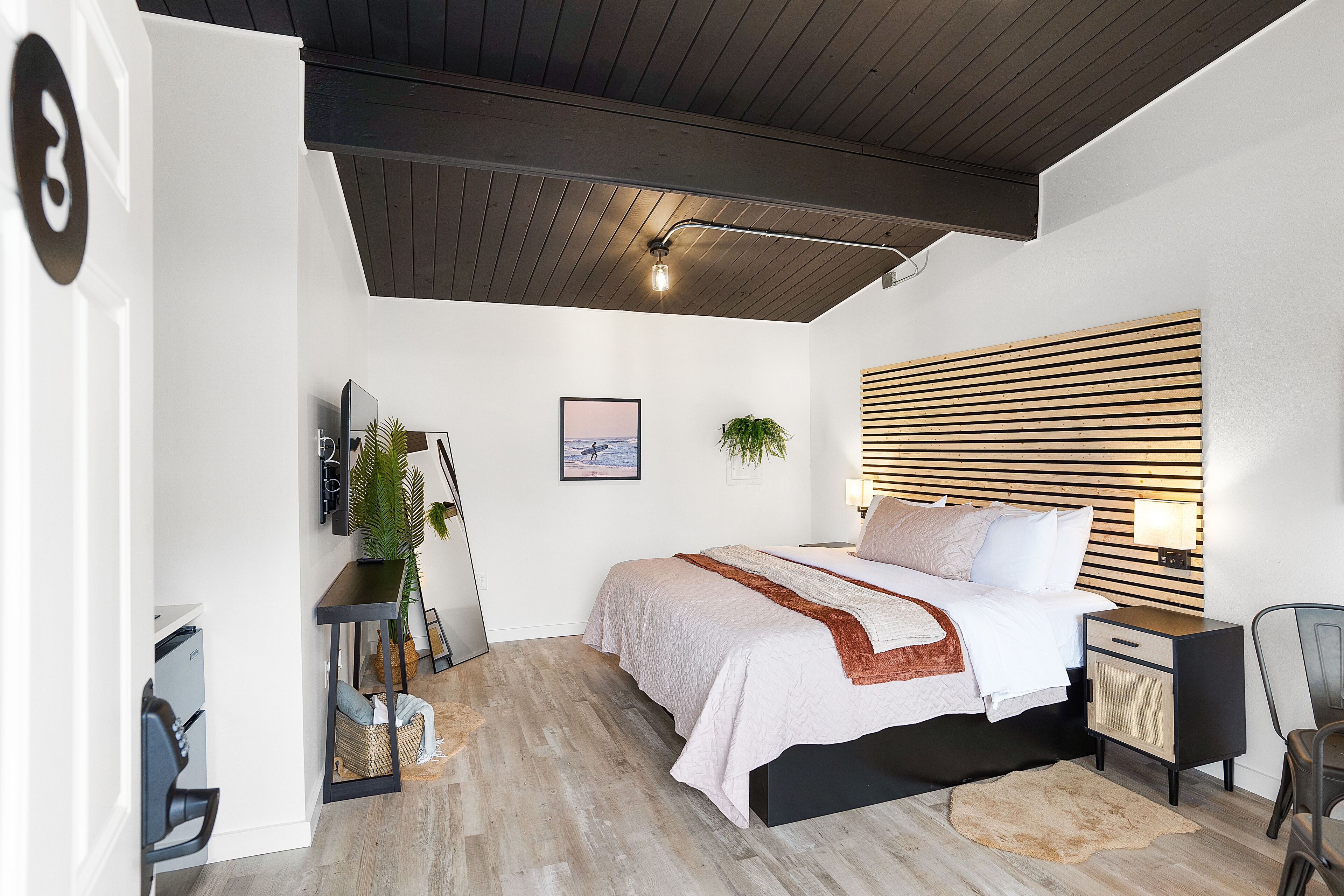 A modern bedroom with a bed, bedside table, lamp, and a view of the outdoors.