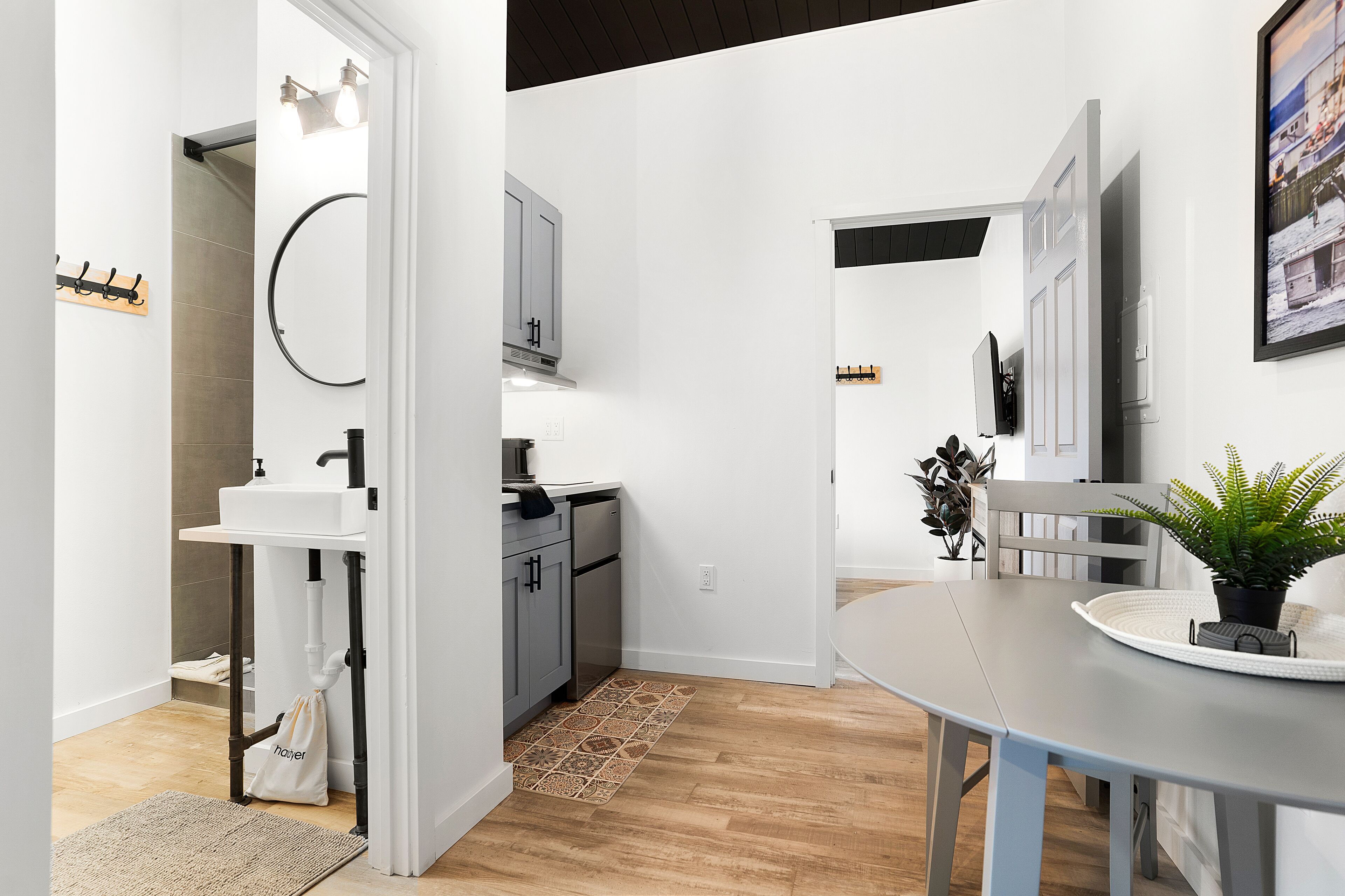A modern kitchen with white cabinets, a sink, and a dining area with a table and chairs.