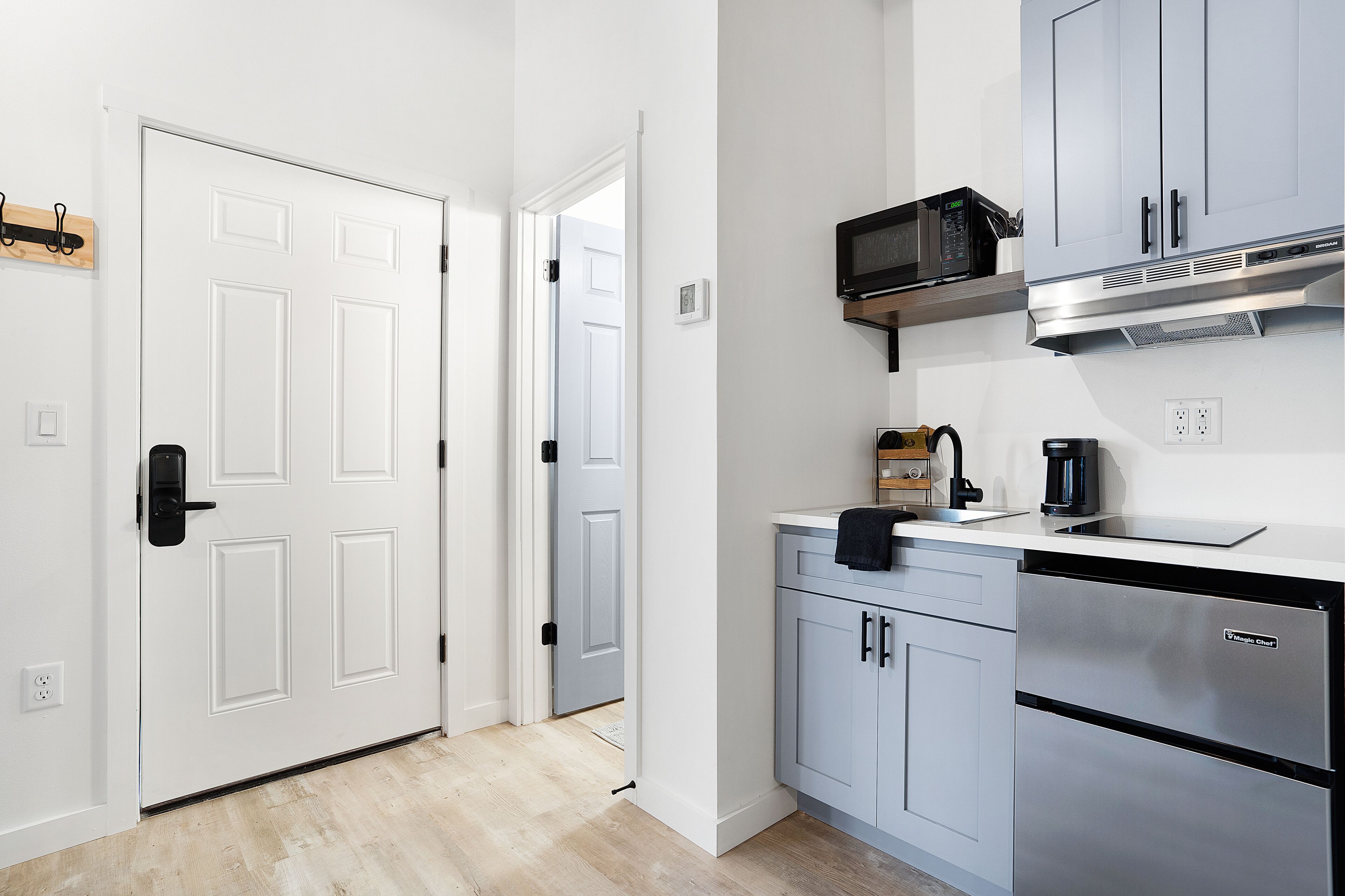 A modern kitchen with white cabinetry, a built-in microwave, and a stainless steel dishwasher.