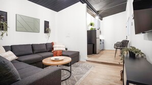 A modern living room with a sectional sofa, a round coffee table, and a TV mounted on the wall. - South Bay Inn  (Westport)
