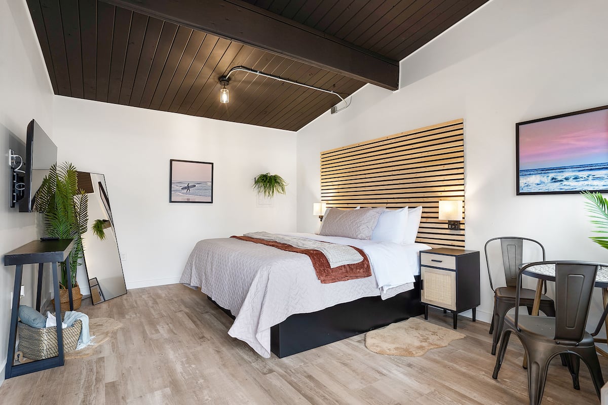A modern bedroom with a bed, bedside tables, a desk, and a chair.