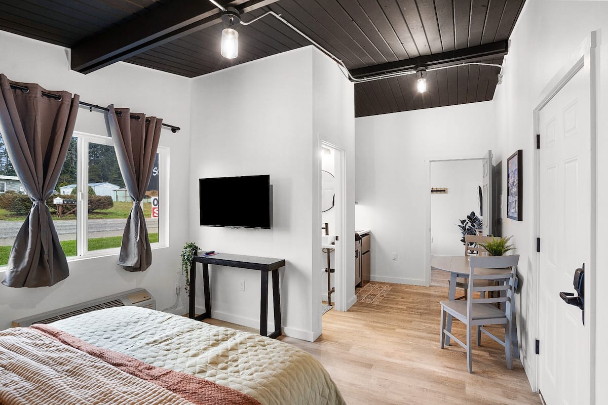 A modern bedroom with a bed, a TV, a desk, and a chair.