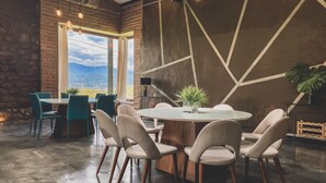 Comedor con una mesa redonda, seis sillas y vistas a montañas a través de amplios ventanales.