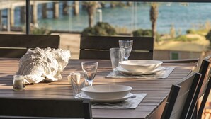A table set for dining with a view of the ocean and a bridge in the background.