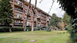 A multi-story residential building with balconies, a grassy courtyard, and surrounding trees. - A stone's throw from San Pietro and Villa Pamphili (Roma)