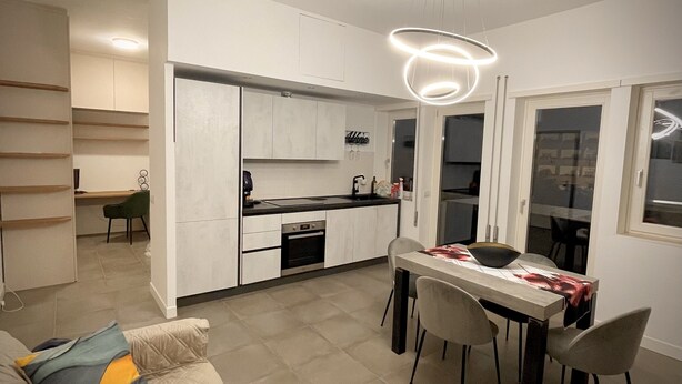 A modern kitchen with integrated dining area, built-in cabinets, and a central island. - A stone's throw from San Pietro and Villa Pamphili (Roma)