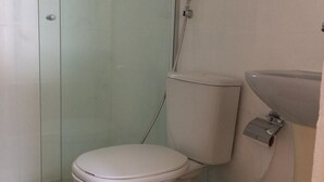 Un baño con inodoro, cabina de ducha de vidrio y lavabo.