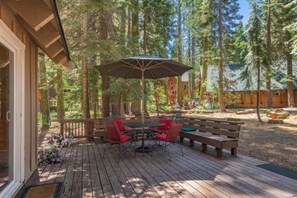 An outdoor deck with a table and chairs, surrounded by trees. - Chamberlands Beach!  Large Family Home! (Homewood)