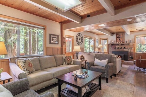 A cozy living room with a sofa, armchairs, a coffee table, and a fireplace.